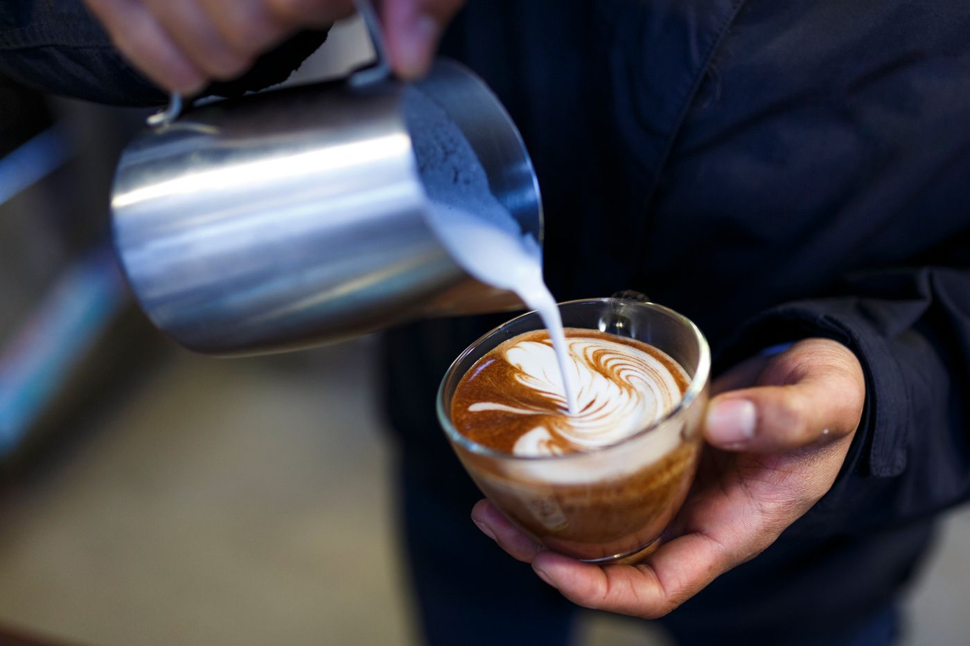 Barista gießt Latte Art in eine Tasse
